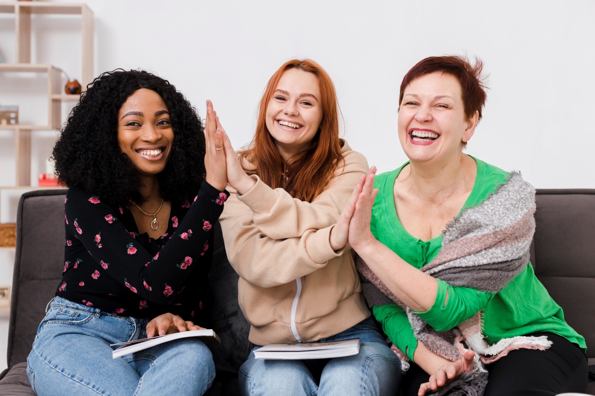Drei fröhliche Frauen sitzen auf einem Sofa